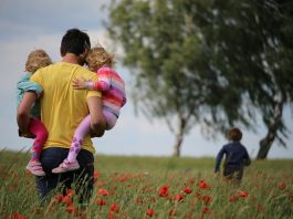 Tout comprendre sur la parentalité : définition, enjeux et accompagnement man carrying to girls on field of red petaled flower